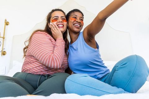 Two friends applying under-eye gel patches while sharing cozy self-care moment in loungewear