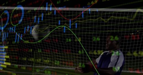 Male Athlete Tracks Ball in Night Goal with Financial Charts