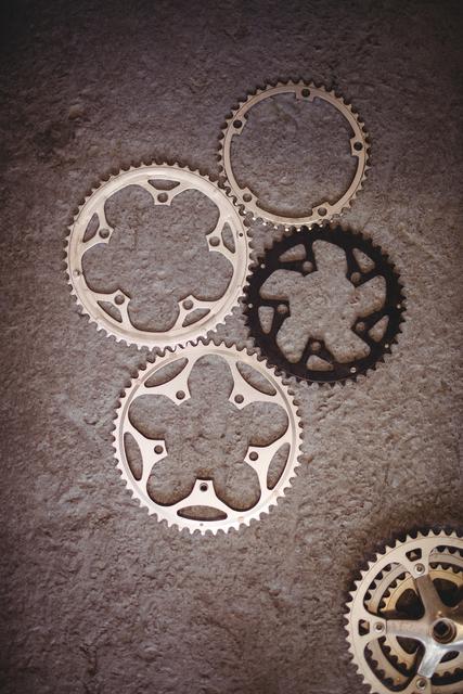 Bicycle gears in a workshop setting. Useful for illustrating bike repair and maintenance concepts, mechanical engineering, and cycling equipment. Ideal for articles, tutorials, and instructional materials on bike maintenance and repair, as well as for engineering and mechanical project visuals.