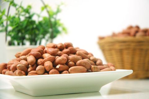 Close-up of raw peanuts in bowl with plants in background