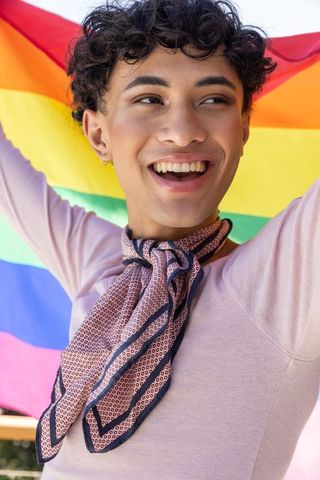 Joyful Individual Holding Rainbow Flag Celebrating Pride Outdoors