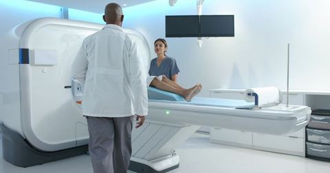 African american radiology team preparing patient for mri scan in modern hospital