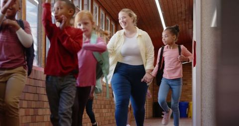 Teacher leading group of diverse children in school hallway