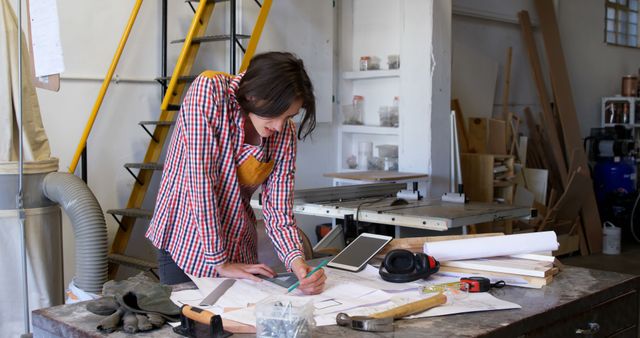 Female Carpenter Working on Design Plans in Workshop - Download Free Stock Images Pikwizard.com