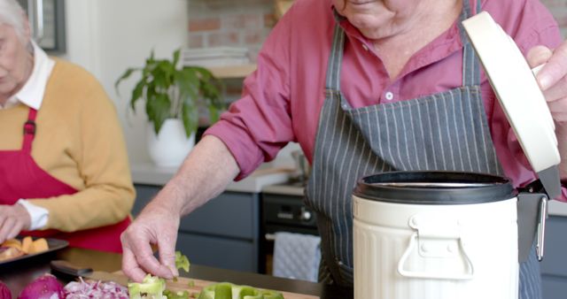 Senior caucasian couple cleaning vegetable peels in kitchen at home, slow motion. Senior lifestyle, food, meal, healthy living, togetherness and domestic life, unaltered.