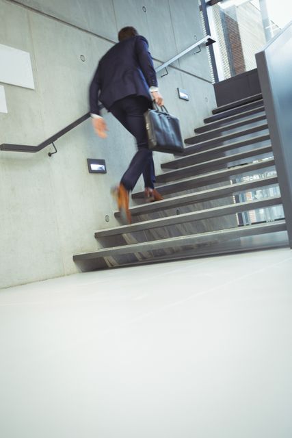Businessman Climbing Stairs in Modern Office Building - Download Free Stock Photos Pikwizard.com