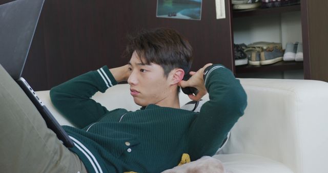 Young Man Wearing Green Sweater Relaxing on Couch While Using Laptop - Download Free Stock Images Pikwizard.com