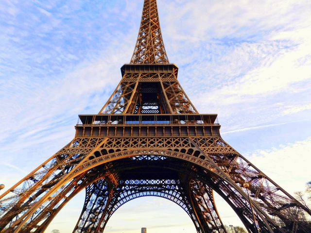 Magnificent view of Eiffel Tower with clear blue sky, ideal for travel blogs, tourism advertisements, postcards, and architectural studies. Image evokes sense of adventure and grandeur, suitable for showcasing Parisian landmarks and cultural heritage.