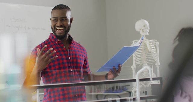Smiling teacher delivering an anatomy lesson in a classroom with a skeletal model in the background. Ideal for educational content, school or university presentations, online courses, and promotional materials for academic institutions.