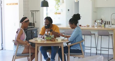 African american family enjoying casual breakfast and salad at modern kitchen table