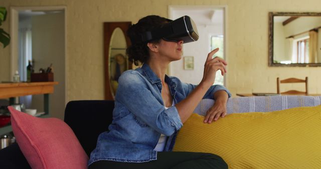 Woman in casual clothing experiencing virtual reality from comfort of home. Ideal for tech blogs, modern lifestyle promotions, VR experiences, and home technology showcases.