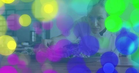 Chef arranging plated salad on prep counter with colorful bokeh overlay and soft focus