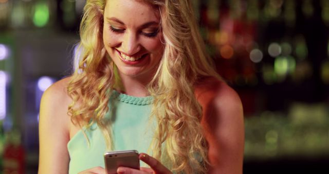 Young Woman Smiling While Using Smartphone at Bar at Night - Download Free Stock Images Pikwizard.com