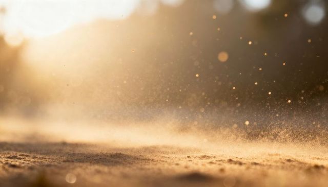 Golden sand drifting in warm backlight, low-angle macro closeup with glowing bokeh, golden hour