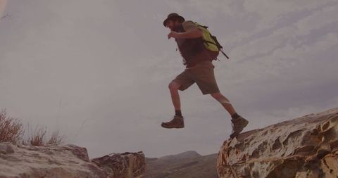 Adventurous hiker jumping between rocky ledges on arid trail