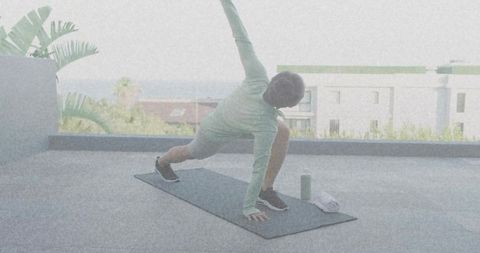 Woman practicing yoga flow on tropical terrace overlooking sea with mat, towel, water bottle