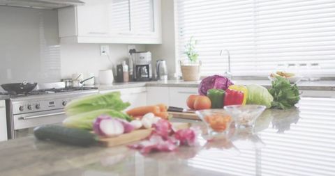 Preparing Fresh Vegetables on Polished Stone Counter with Knife, Cutting Board, Bowls