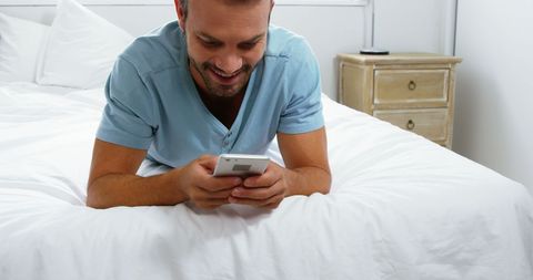 Young Man Relaxing Using Smartphone on White Bed - Download Free Stock Images Pikwizard.com