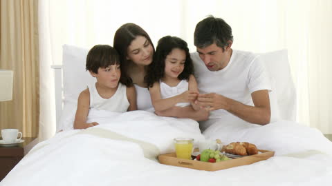 Joyful Family Enjoying Breakfast in Bed Together