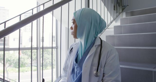 Thoughtful Female Doctor in Hijab Standing on Stairs of Modern Hospital - Download Free Stock Images Pikwizard.com