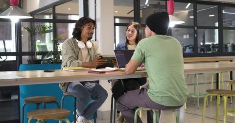 Young professionals collaborating at high communal table in modern bright coworking space