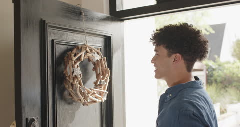 Man Hanging Rustic Christmas Wreath on Front Door