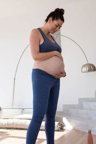 Expectant Mother in Activewear Embracing Pregnancy at Home