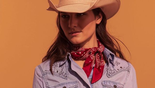 Fashionable cowgirl posing with red bandana and cowboy hat