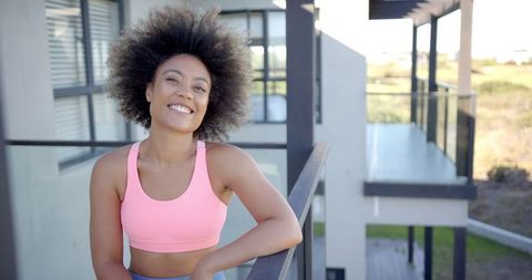 Smiling Woman in Sports Bra Enjoying Sunny Balcony