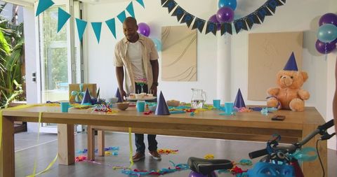 Man arranging colorful party table with balloons and hats