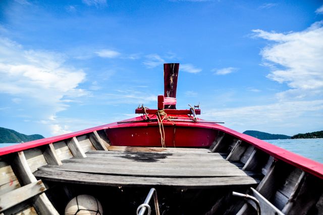 Photo depicts bow of red boat facing clear blue ocean and sky. Suitable for travel websites, adventure blogs, tourism advertisements, and summer holiday promotions. Emphasizes themes of maritime exploration, tranquility, and summertime relaxation.