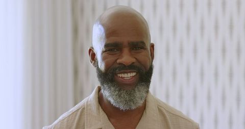 Black man smiling joyfully at indoor wedding celebration