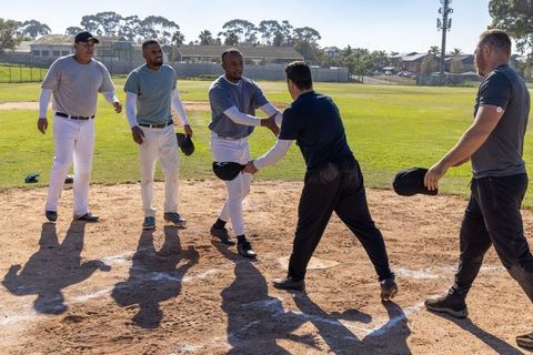 Shaking hands exchanging helmets after inning on sunlit community baseball diamond