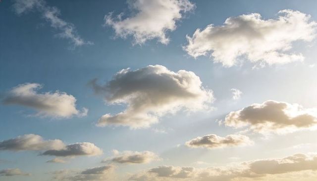 Drifting Golden-Edged Cumulus Clouds Over Vast Calm Blue Sky at Sunset Glow