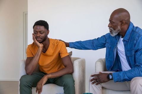 Father offering comfort to concerned son in living room
