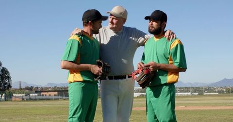 Senior Coach Mentoring Two Baseball Players During Pregame Huddle on Field