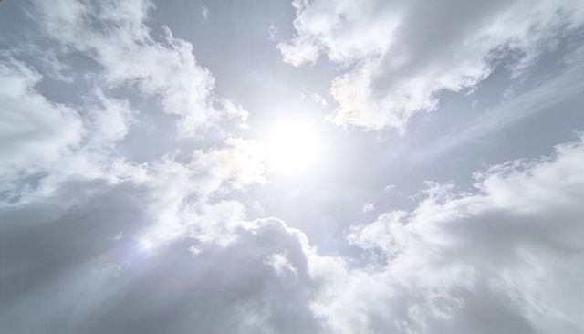 Sun shining through dramatic cloudscape casting sunbeams with soft lens flare, sunrays