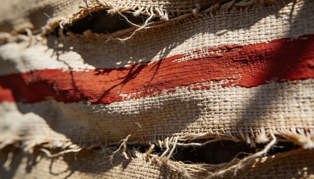 Weathered burlap featuring red stripe and frayed holes close-up texture for rustic design
