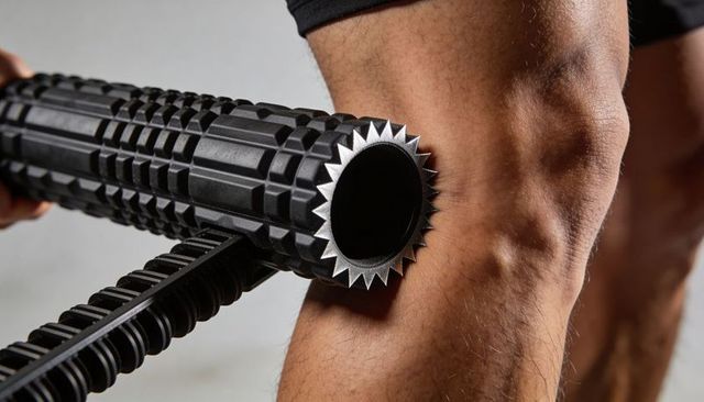 Athlete massaging quadriceps with textured foam roller closeup