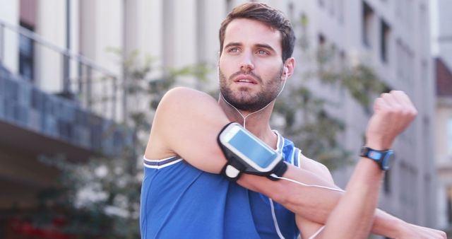 Man stretching while wearing fitness gadgets during outdoor workout - Download Free Stock Images Pikwizard.com