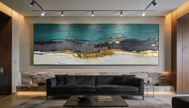 Featuring wide textured abstract painting with gold accents above charcoal sofa in living room