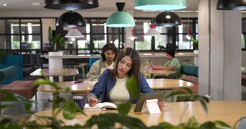 African american woman studying with tablet and notebook in modern coworking space