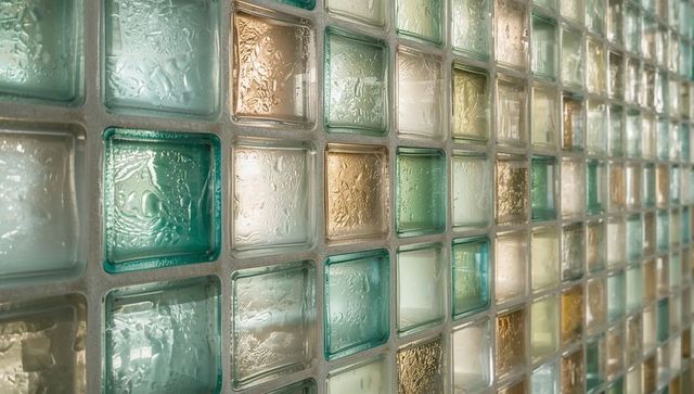 Textured glass block wall receding with teal and amber squares, light glimmering