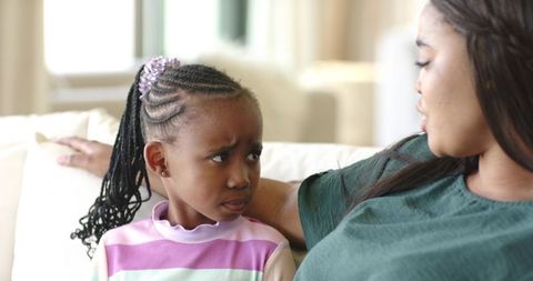 African american mother comforting worried daughter during gentle conversation on couch