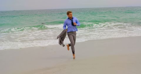 Confident Businessman in Suit Irreverently Running on Serene Beach - Download Free Stock Images Pikwizard.com