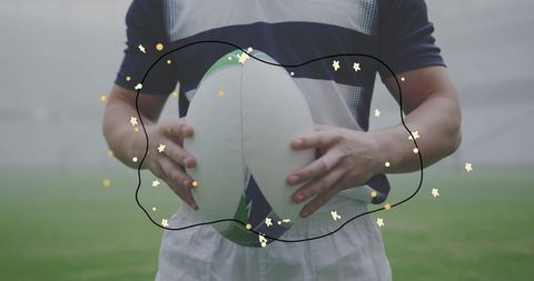 Rugby player holding ball closeup hand grip on oval ball with doodle star overlay