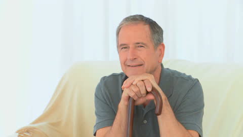 Mature Man Sitting with Cane Smiling in Living Room