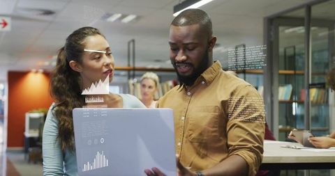 Collaborating on data dashboard using laptop in open office teamwork environment