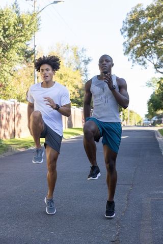 Athletic friends doing high-knee drills in suburban street