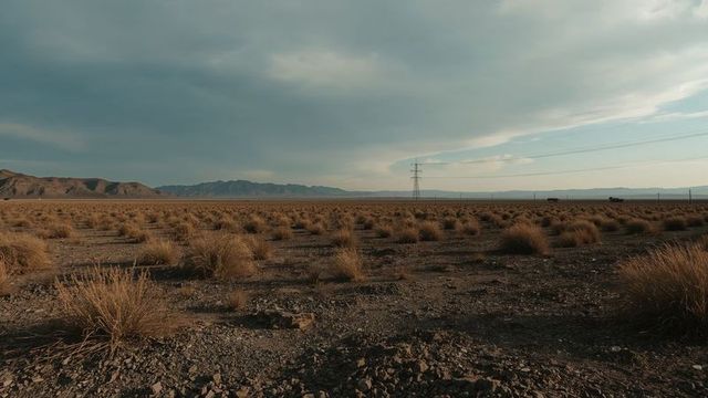 Vast Desert Plain with Transmission Towers and Distant Mountains